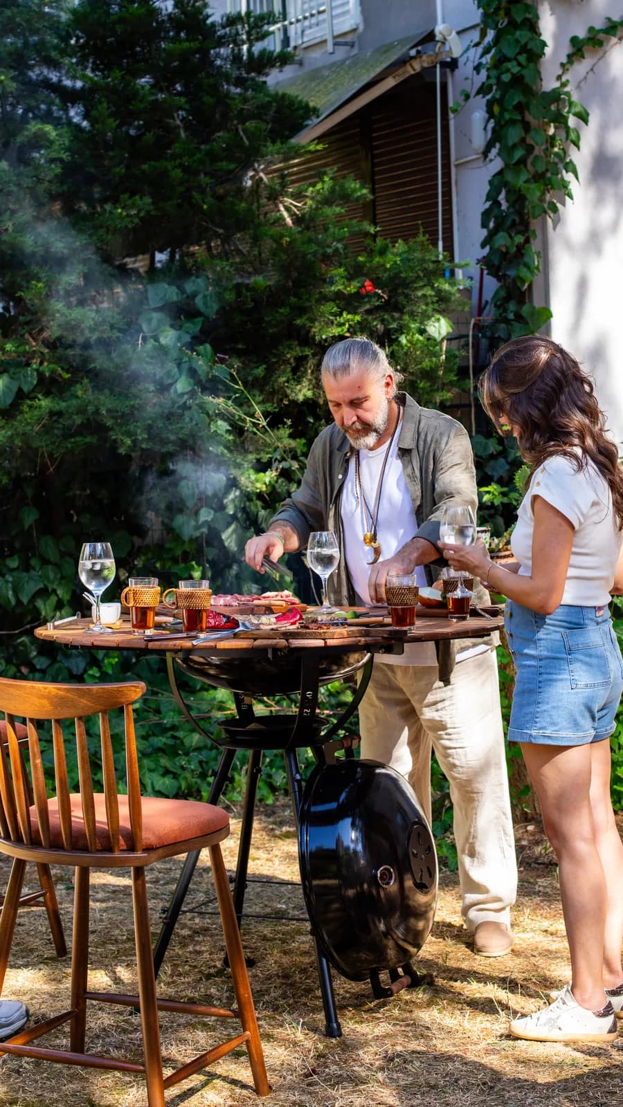 Bahçede BAZZ360 mangallı masa başında mangal keyfi yapan çift