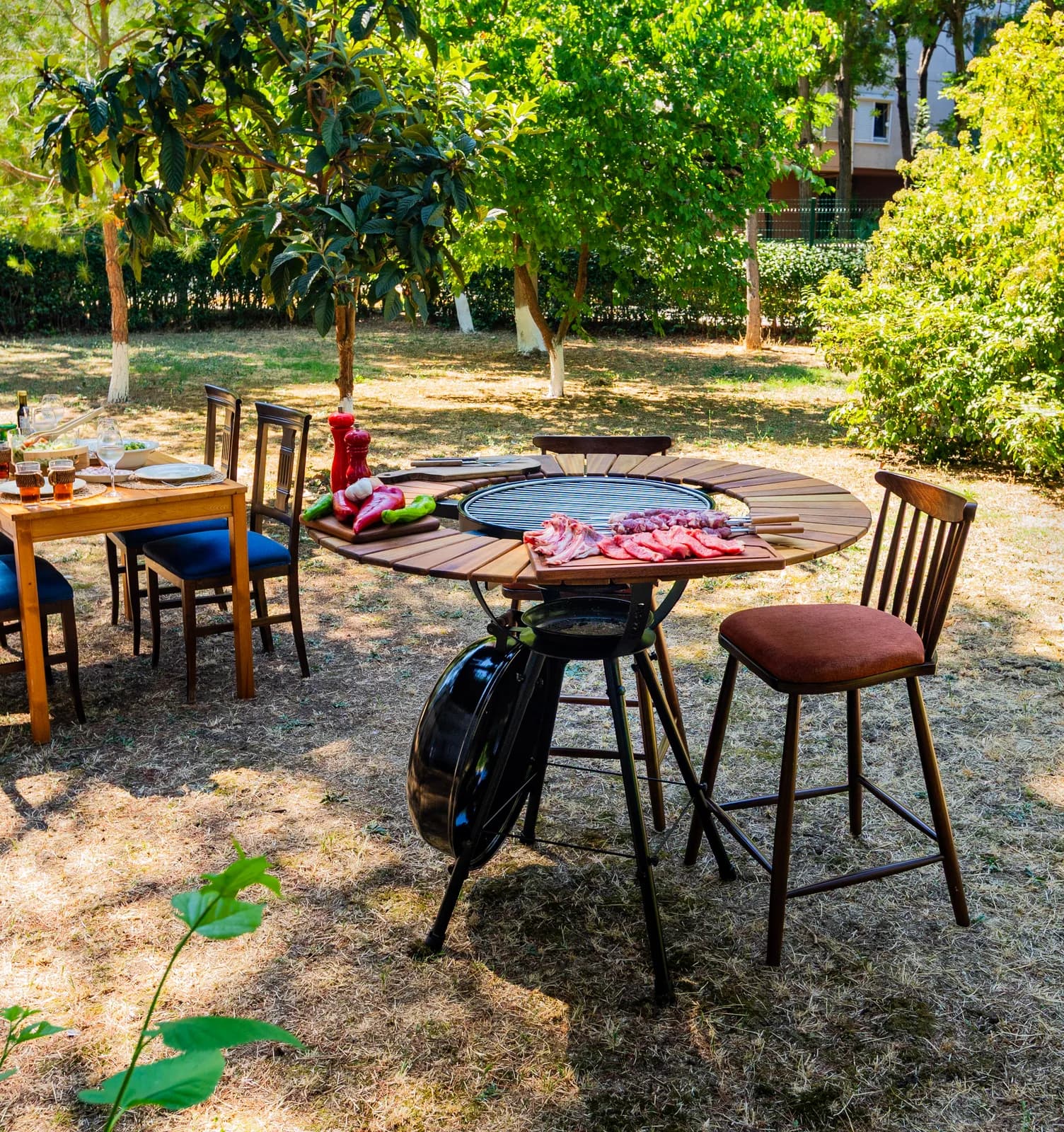 BAZZ360 mangallı masa, bahçede tabureler ve sandalyelerle kurulu